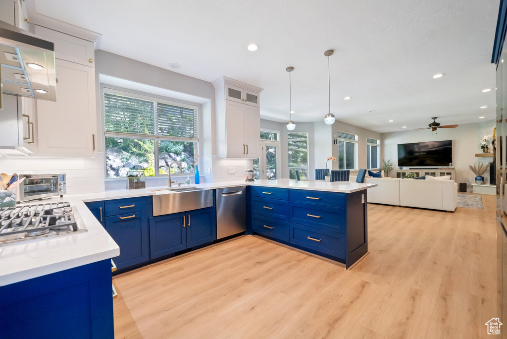 Kitchen featuring kitchen peninsula, stainless steel appliances, blue cabinetry, white cabinetry, and sink