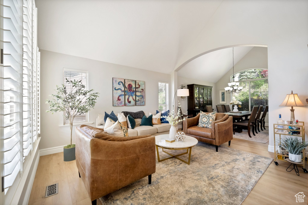 Living room featuring wood-type flooring, an inviting chandelier, and lofted ceiling