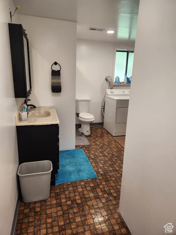 Bathroom featuring tile floors, toilet, washer / dryer, and vanity