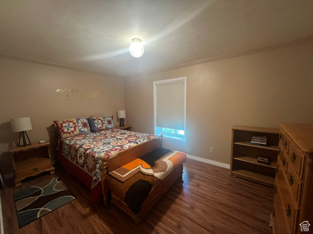 Bedroom featuring ornamental molding and dark wood-type flooring