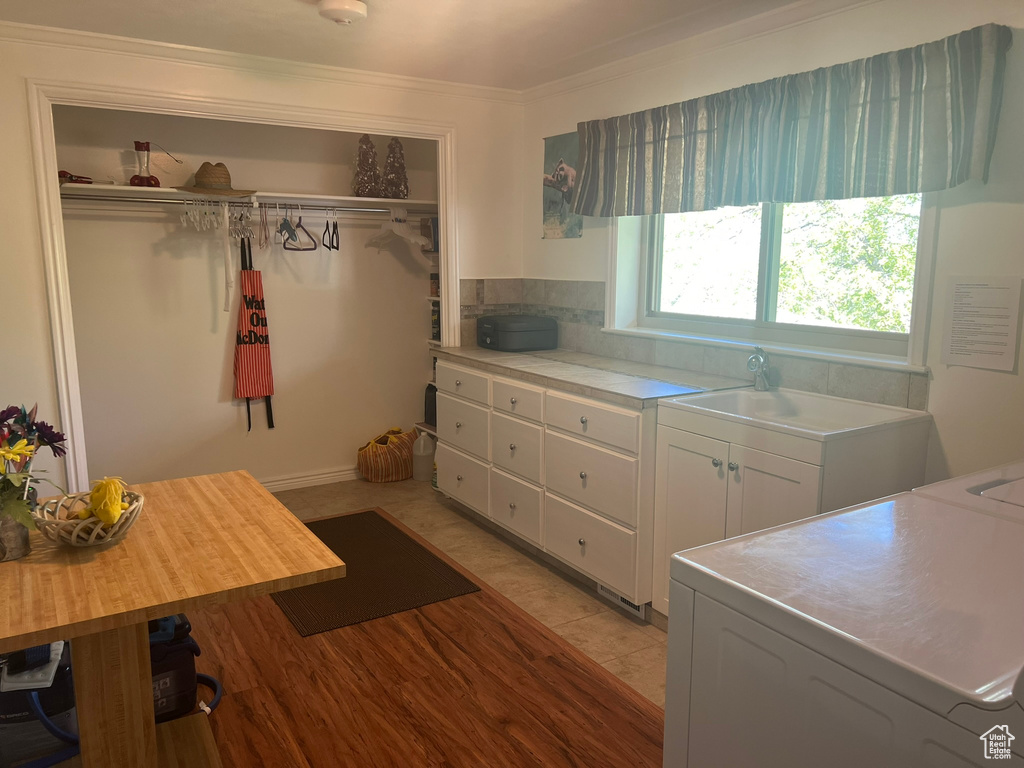 Kitchen with white cabinetry, light tile flooring, tasteful backsplash, and washer / dryer