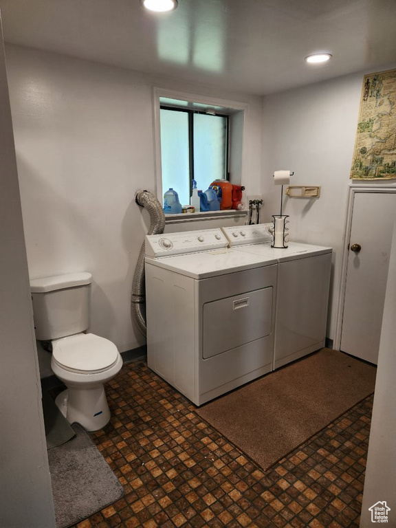 Bathroom with tile floors, washer and clothes dryer, toilet, and vanity