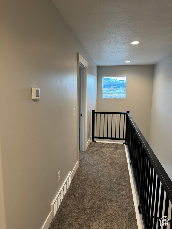 Corridor featuring dark colored carpet