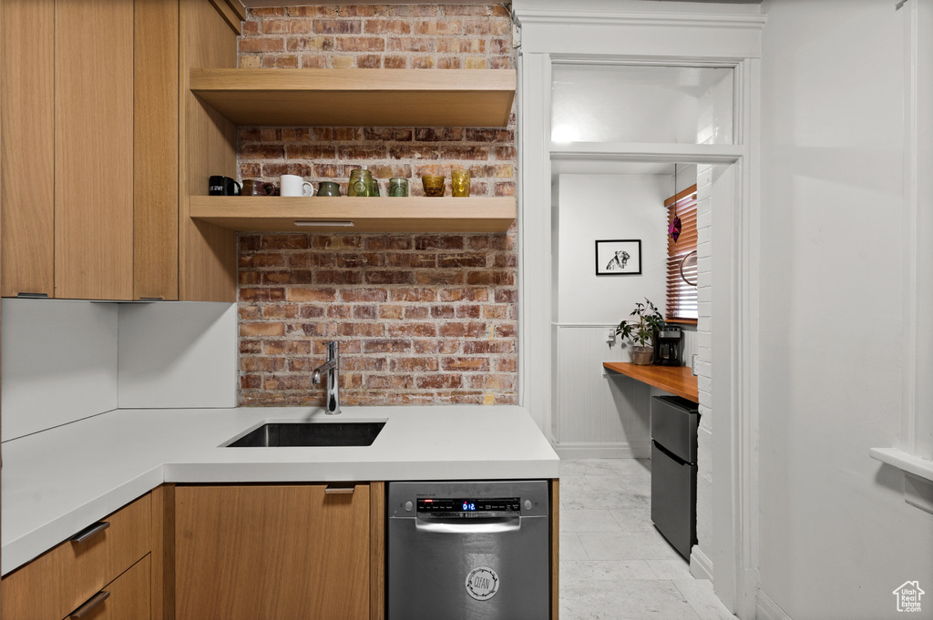 Kitchen featuring sink, dishwashing machine, stainless steel refrigerator, and light tile floors