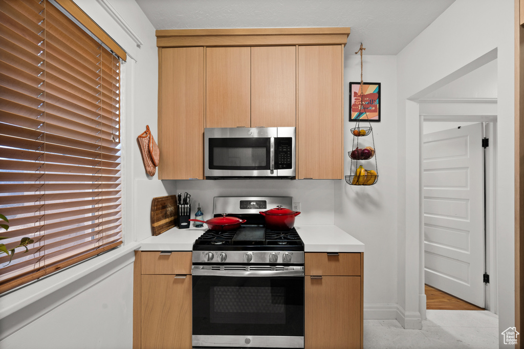 Kitchen featuring appliances with stainless steel finishes, light brown cabinetry, and light tile floors