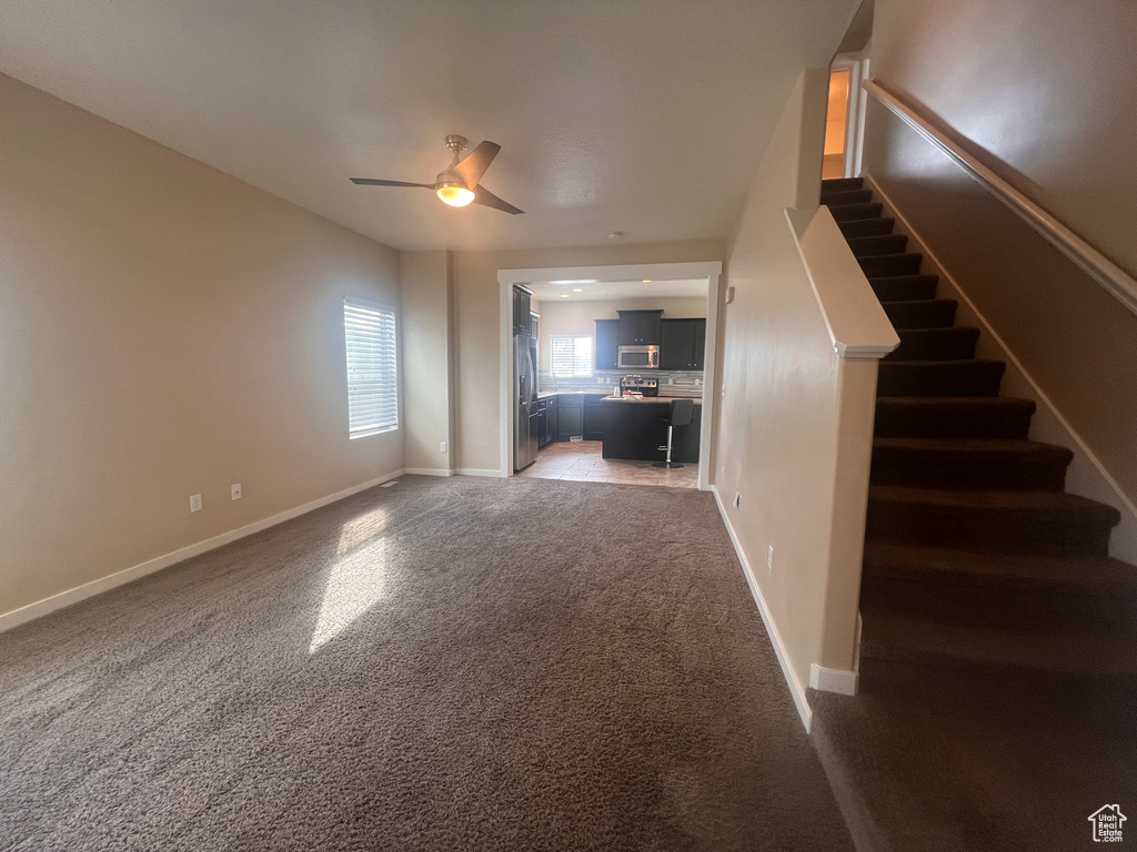 Unfurnished living room featuring carpet and ceiling fan