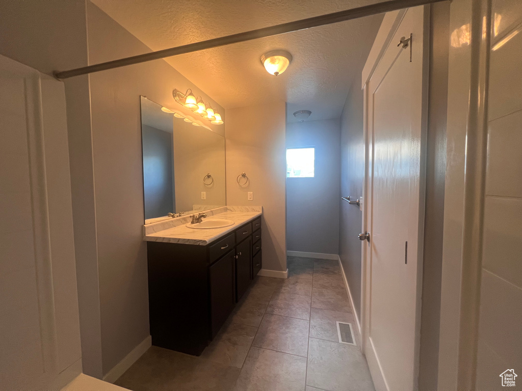 Bathroom with tile flooring, vanity, and a textured ceiling
