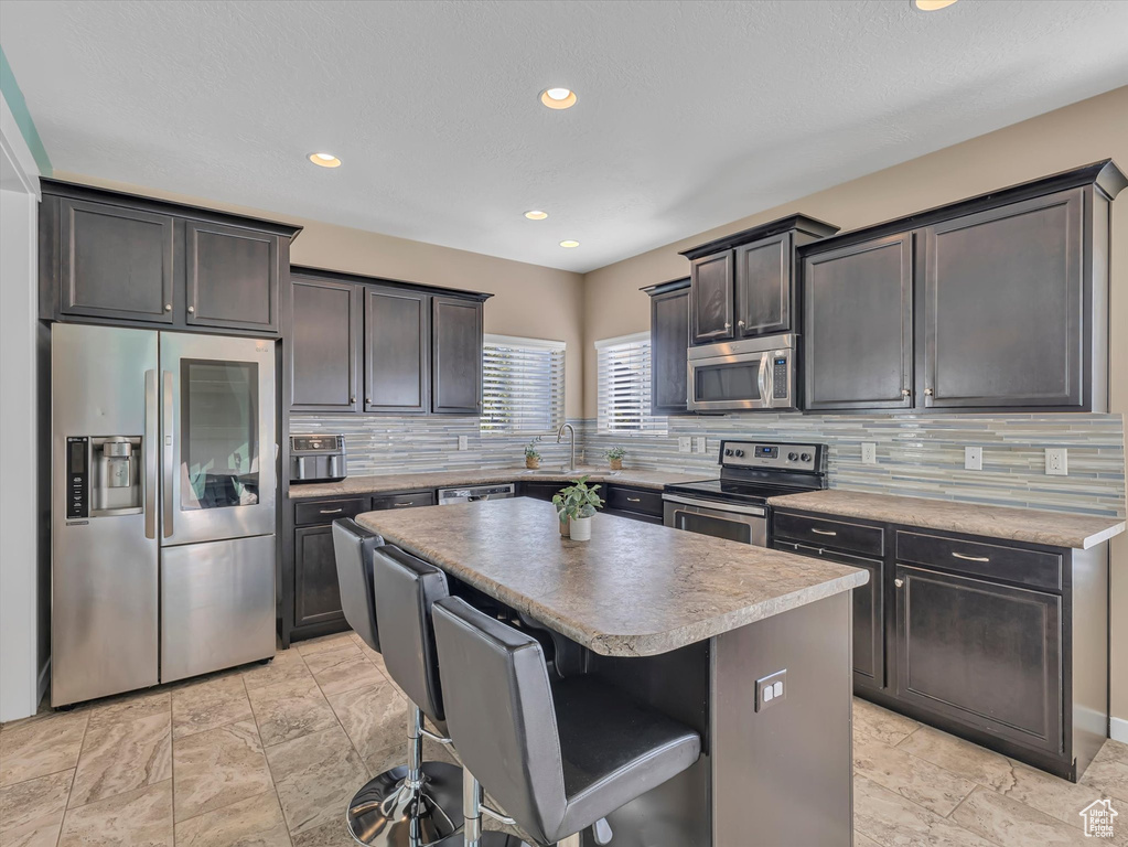 Kitchen with a breakfast bar area, tasteful backsplash, and appliances with stainless steel finishes