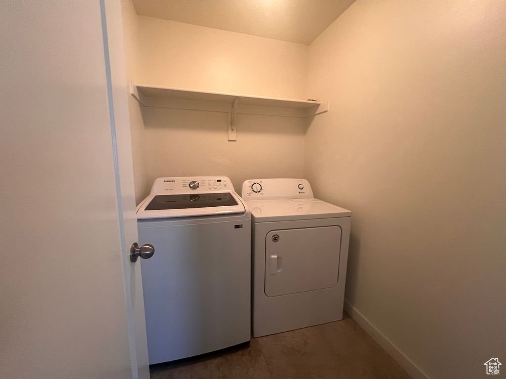 Laundry room featuring dark tile floors and washing machine and dryer