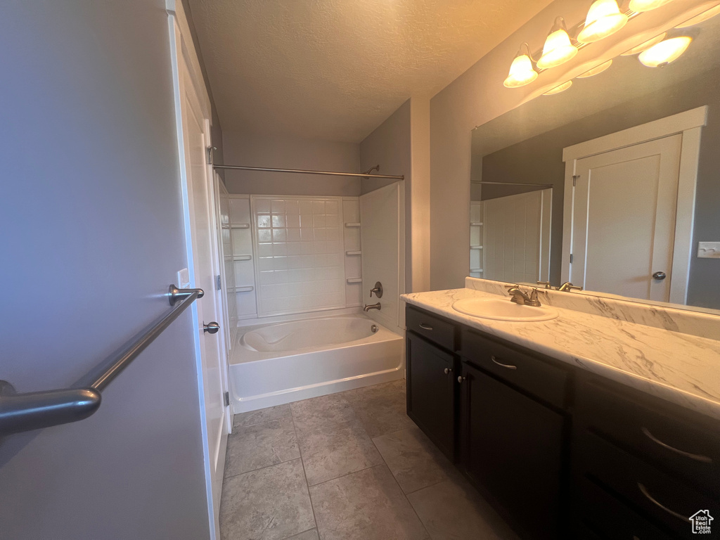 Bathroom featuring shower / bath combination, vanity with extensive cabinet space, a textured ceiling, and tile floors