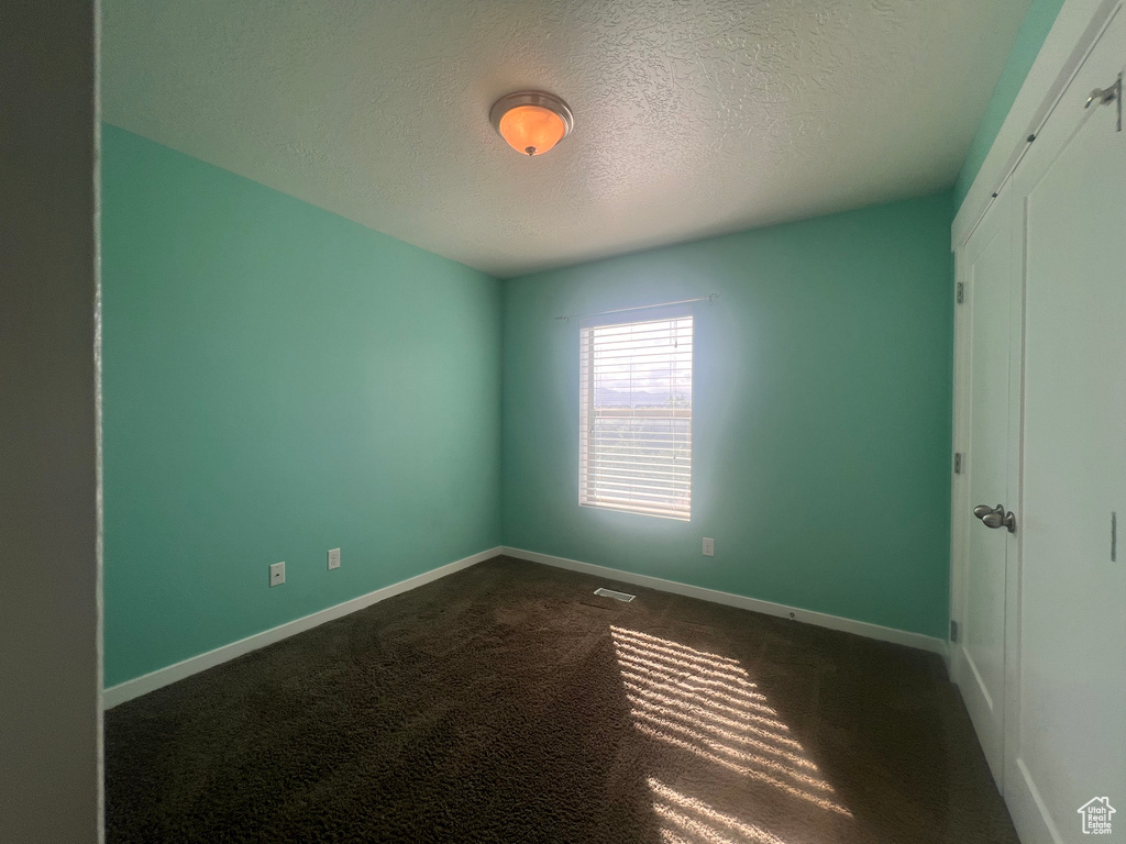 Spare room featuring carpet flooring and a textured ceiling