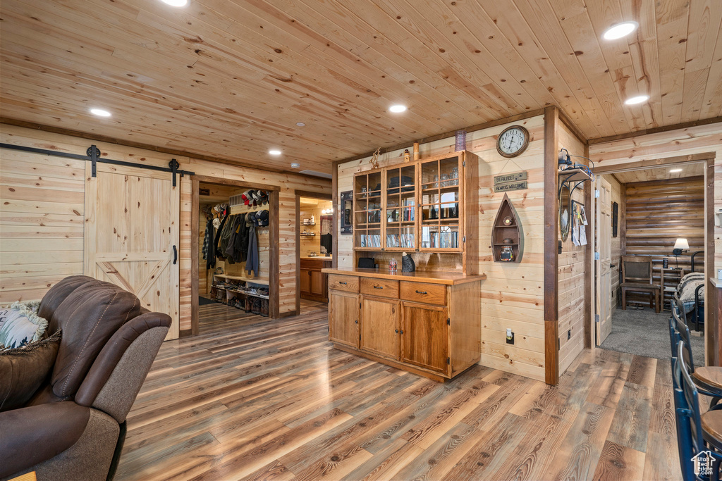 Kitchen featuring log walls, hardwood / wood-style floors, a barn door, and wood ceiling