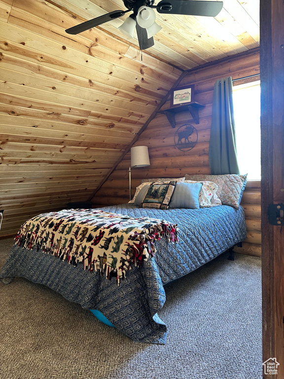 Bedroom with ceiling fan, vaulted ceiling, wood ceiling, rustic walls, and carpet