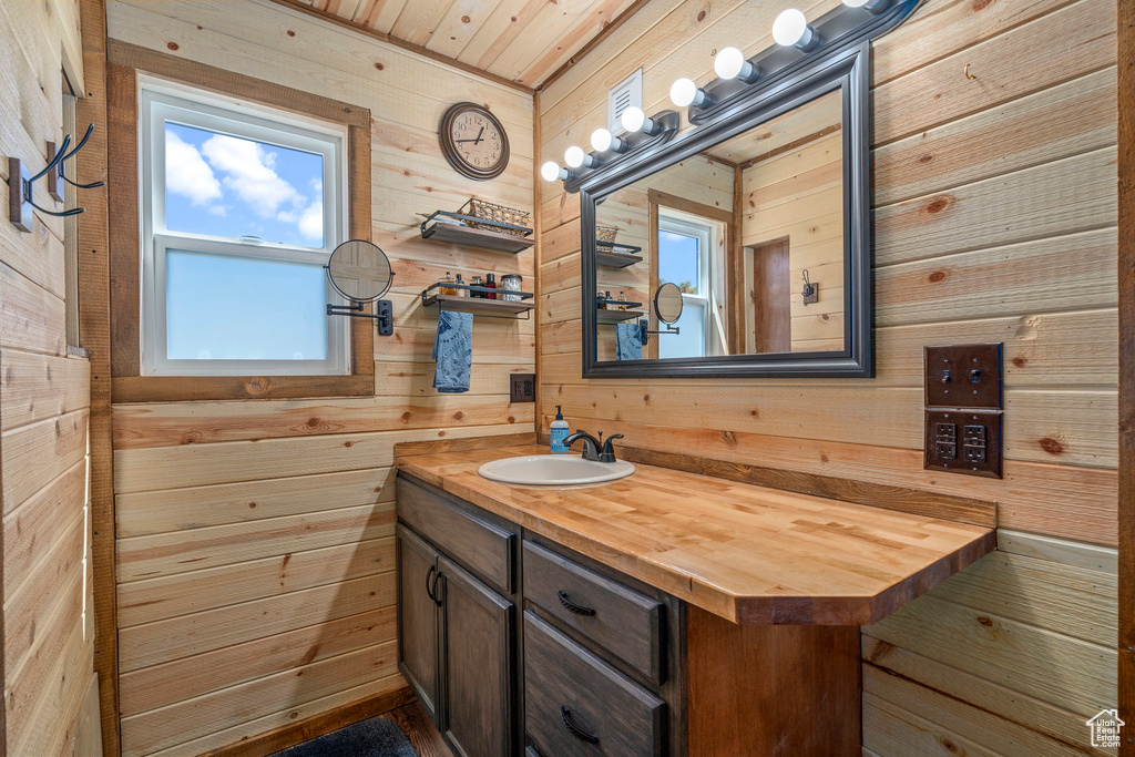 Bathroom with wood ceiling, a healthy amount of sunlight, wooden walls, and vanity