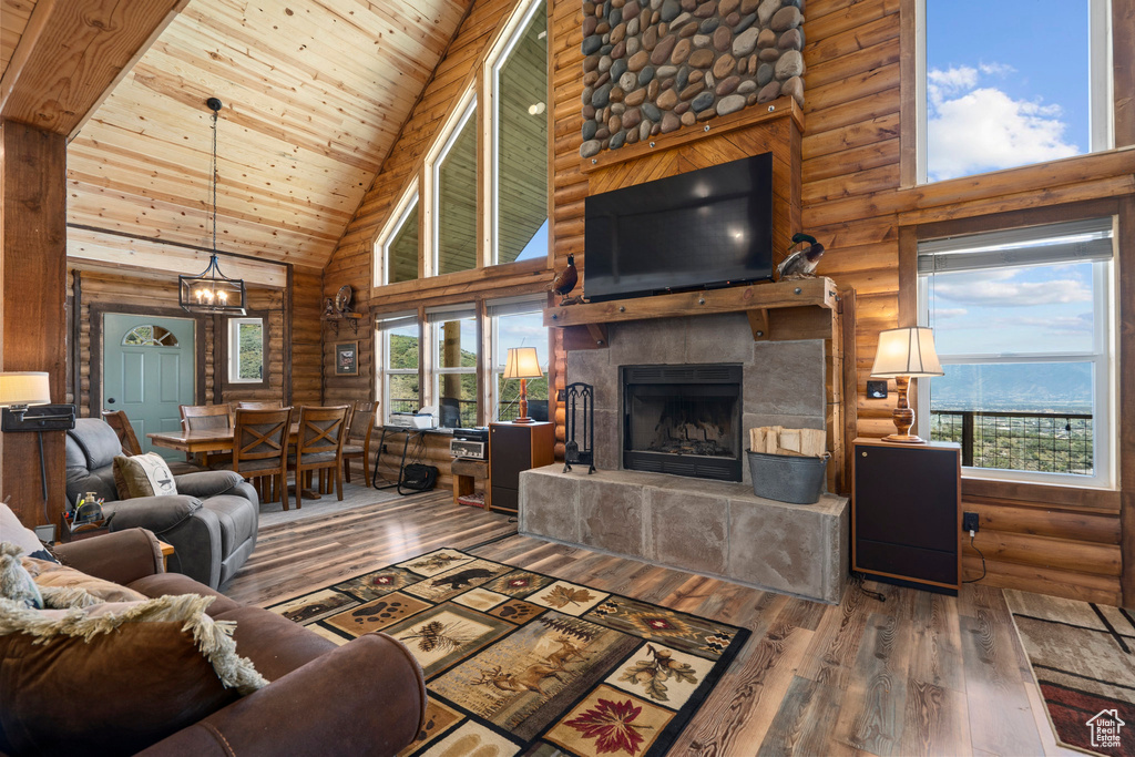 Living room with high vaulted ceiling, hardwood / wood-style floors, plenty of natural light, and log walls