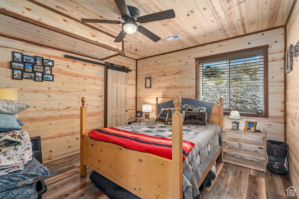 Bedroom with wooden walls, ceiling fan, wood ceiling, and dark wood-type flooring