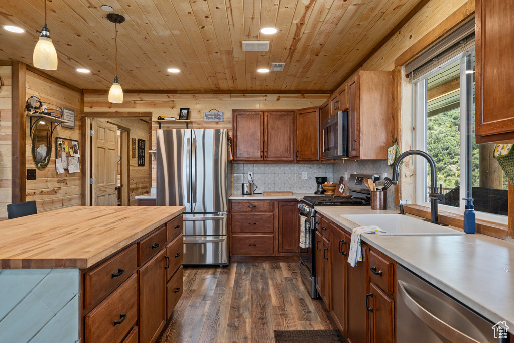 Kitchen featuring stainless steel appliances, butcher block counters, pendant lighting, wood ceiling, and dark hardwood / wood-style flooring