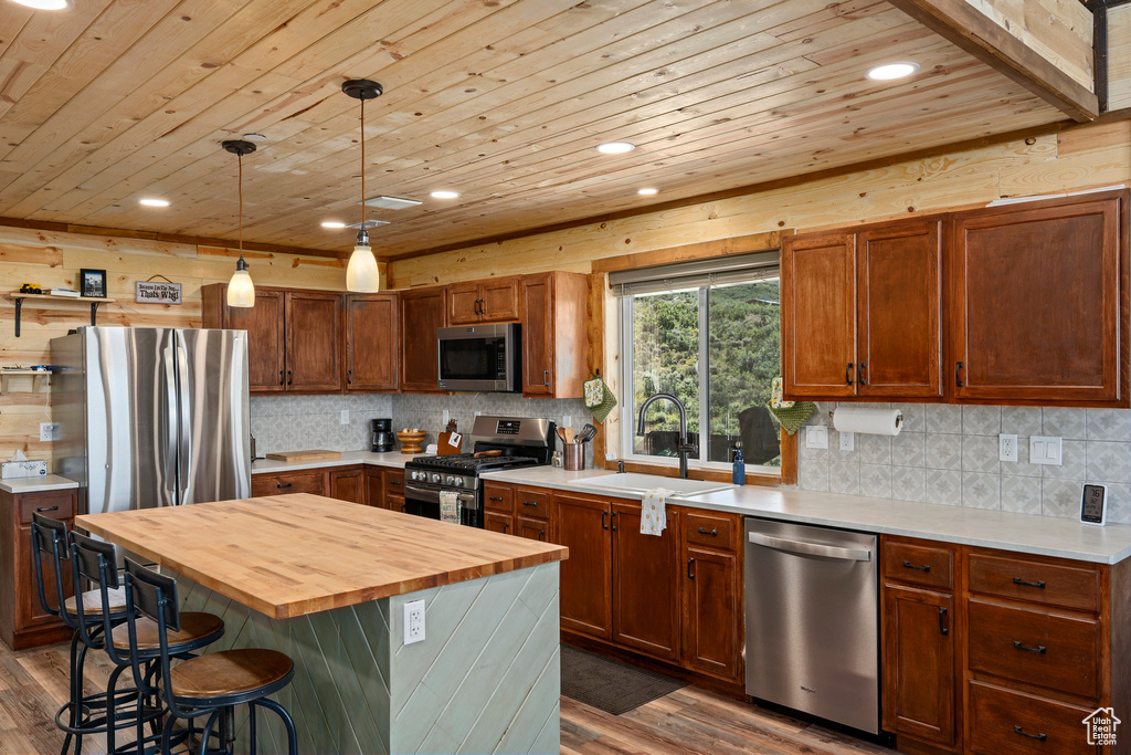 Kitchen featuring a kitchen breakfast bar, stainless steel appliances, butcher block counters, dark wood-type flooring, and a center island