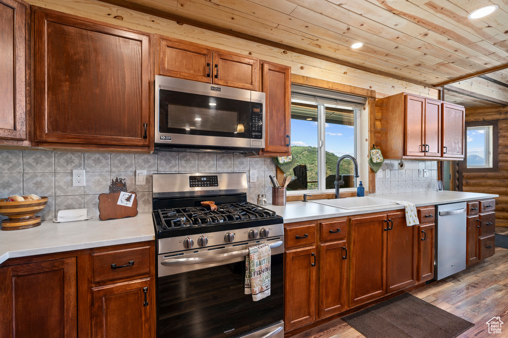 Kitchen featuring appliances with stainless steel finishes, sink, dark hardwood / wood-style floors, and backsplash
