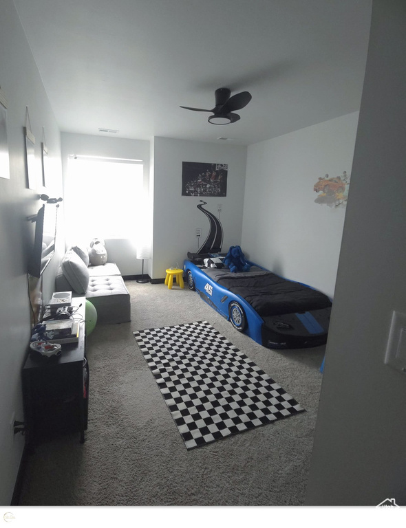 Carpeted bedroom featuring ceiling fan