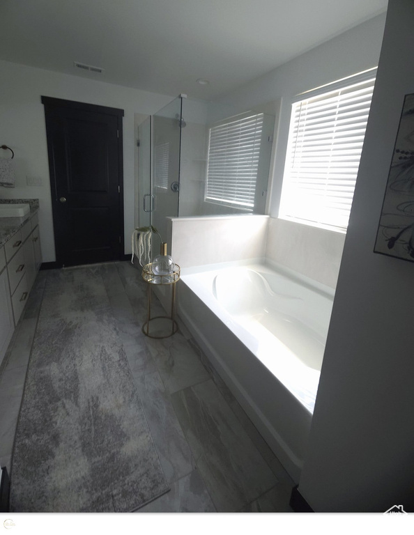 Bathroom featuring tile flooring, independent shower and bath, and vanity