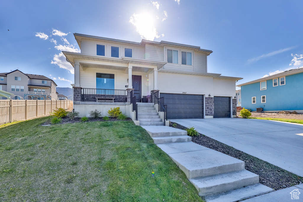 View of front of home featuring a front yard, a porch, and a garage