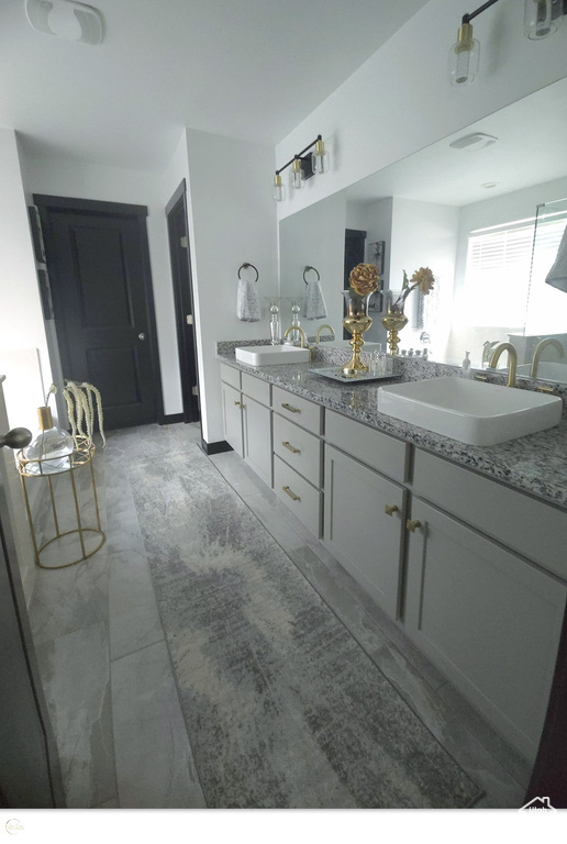 Bathroom featuring tile floors, dual sinks, and vanity with extensive cabinet space