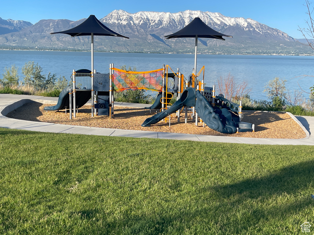 View of jungle gym with a yard and a water and mountain view