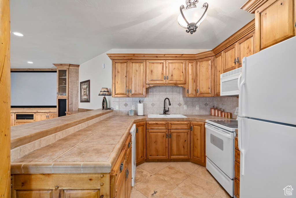 Kitchen with white appliances, sink, tasteful backsplash, and light tile floors