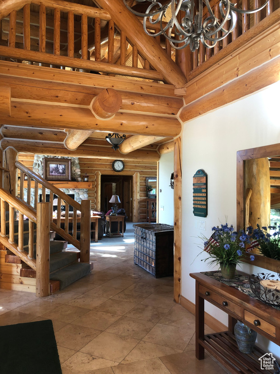 Interior space with a high ceiling, tile flooring, an inviting chandelier, and rustic walls