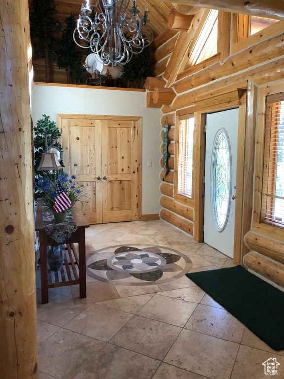 Entryway featuring a healthy amount of sunlight, a notable chandelier, tile flooring, and rustic walls