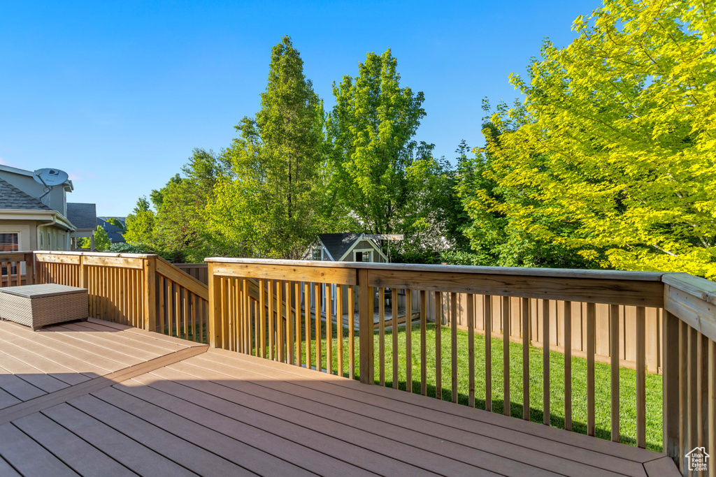 Wooden deck featuring a lawn and a storage shed