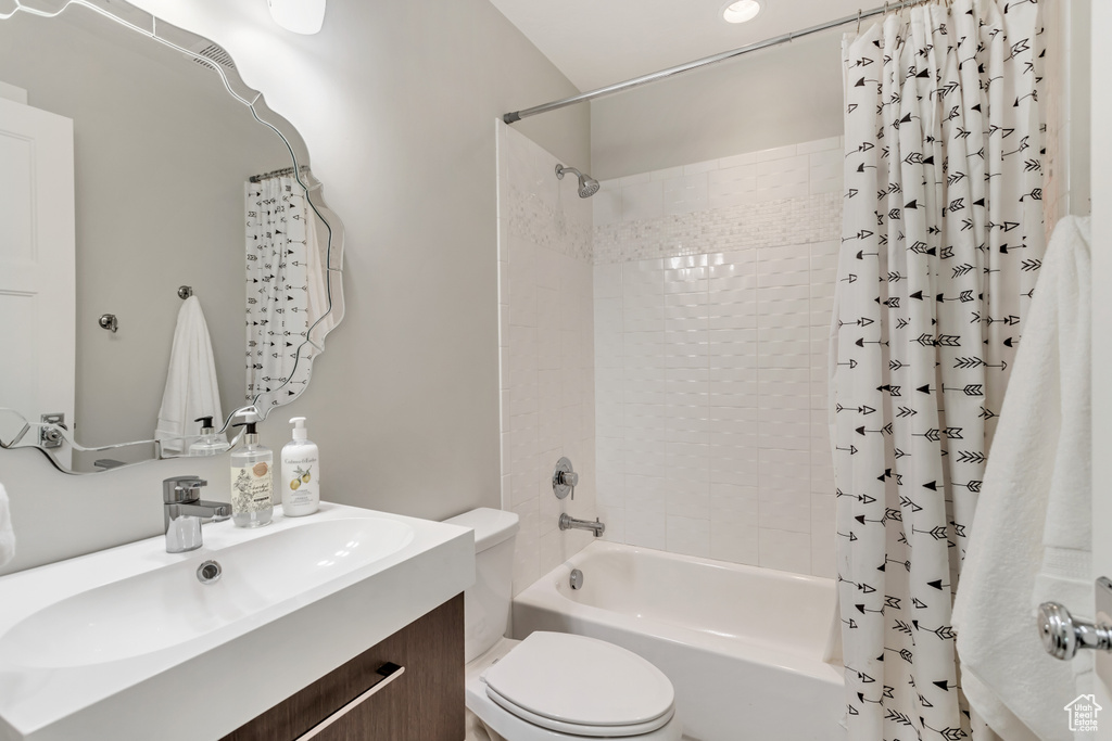 Full bathroom with vanity with extensive cabinet space, toilet, and shower / tub combo with curtain
