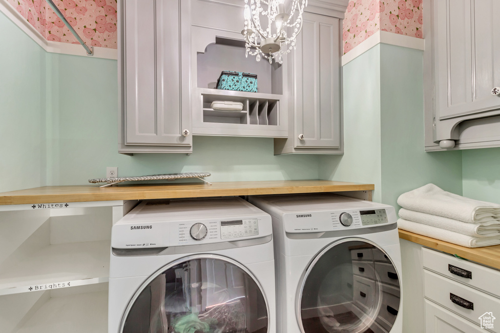 Laundry area with independent washer and dryer, cabinets, and a chandelier
