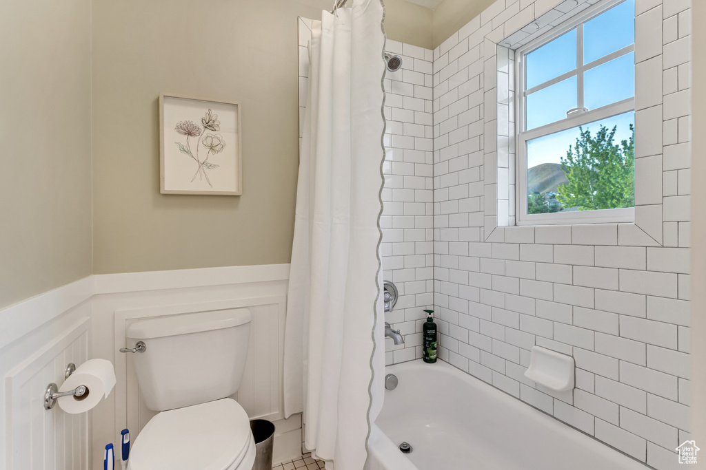 Bathroom with shower / bath combo with shower curtain, toilet, and tile floors