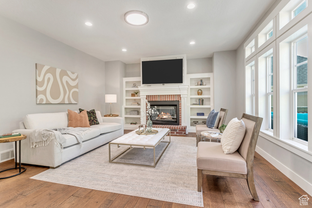 Living room featuring hardwood / wood-style floors, built in features, and a fireplace