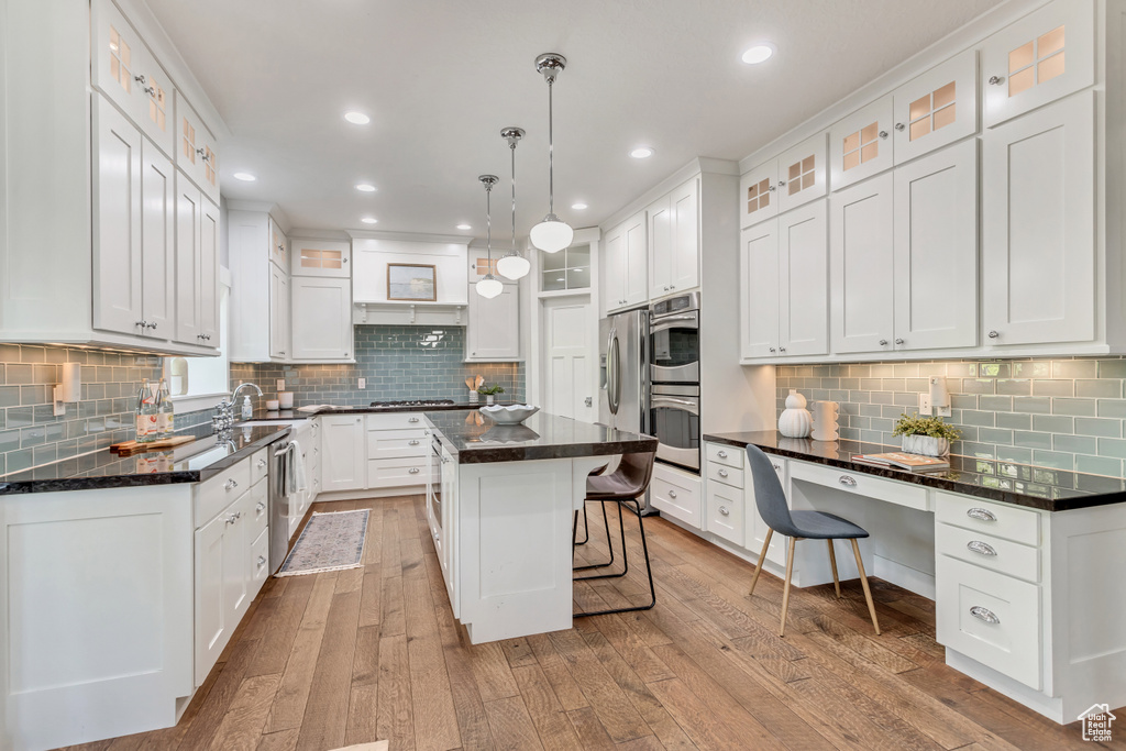 Kitchen with a kitchen island, backsplash, hanging light fixtures, light wood-type flooring, and white cabinets