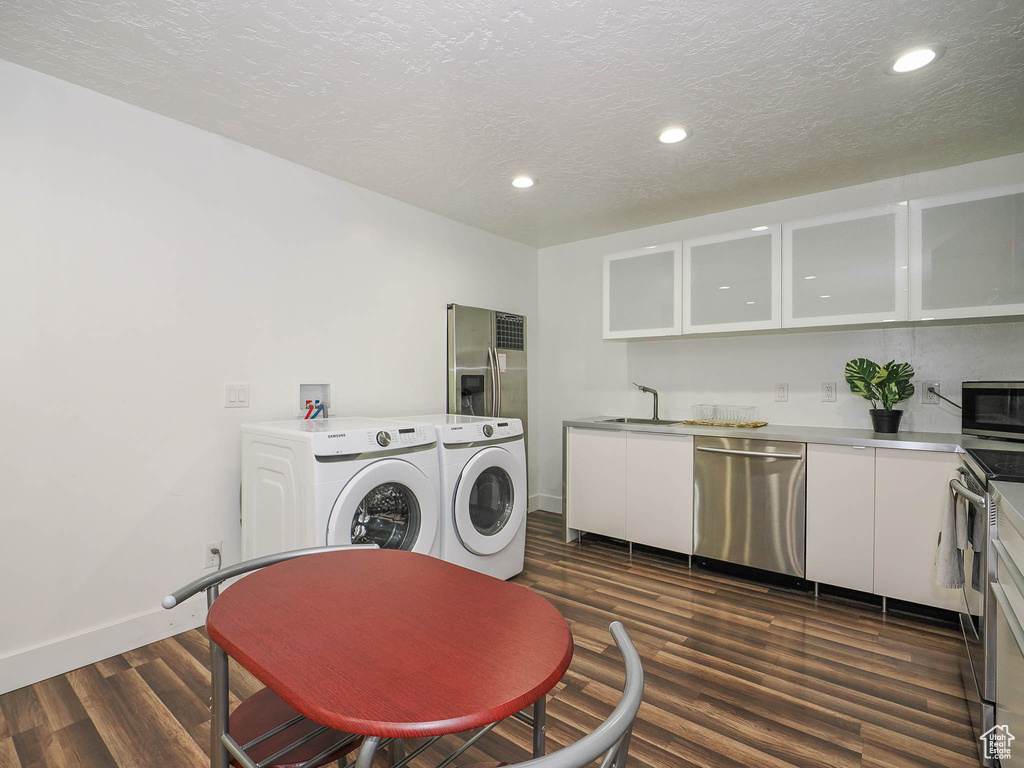 Laundry area with separate washer and dryer, a textured ceiling, sink, and dark hardwood / wood-style flooring