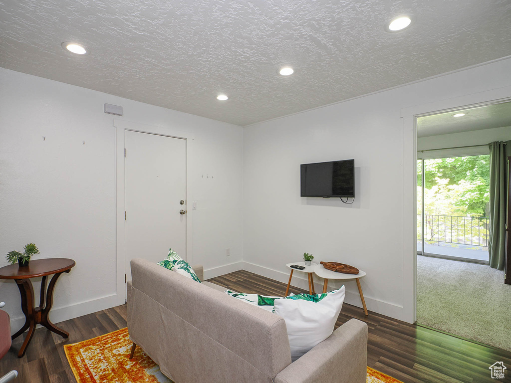 Living room featuring a textured ceiling and dark carpet