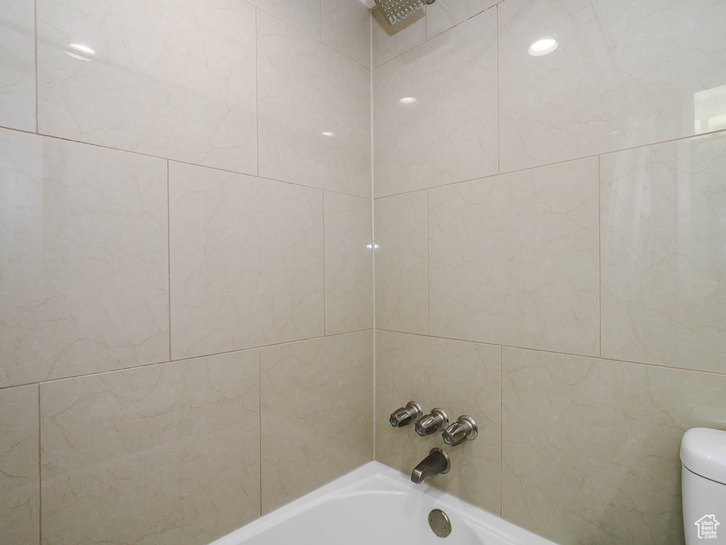 Bathroom featuring tiled shower / bath and toilet