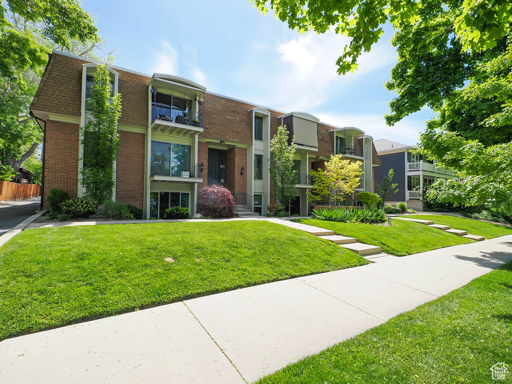 View of front of house with a balcony and a front lawn