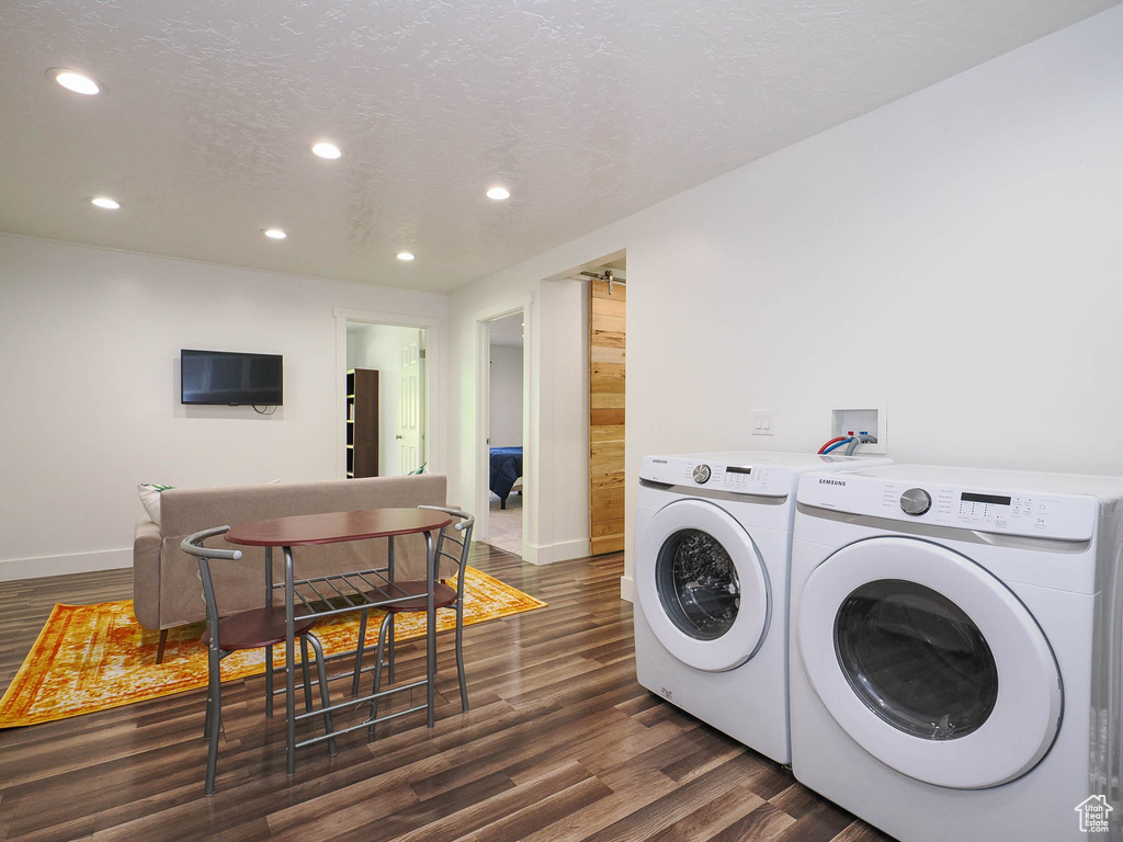 Clothes washing area featuring washer and clothes dryer, washer hookup, a barn door, dark wood-type flooring, and a textured ceiling