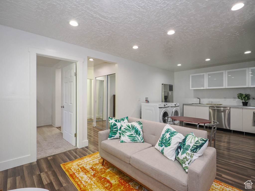 Living room featuring washer and dryer, a textured ceiling, and hardwood / wood-style floors