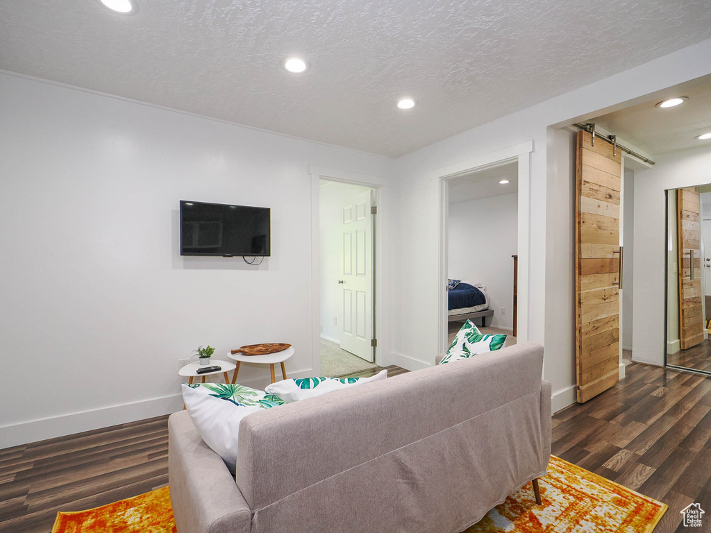 Living room with dark hardwood / wood-style floors, a barn door, and a textured ceiling