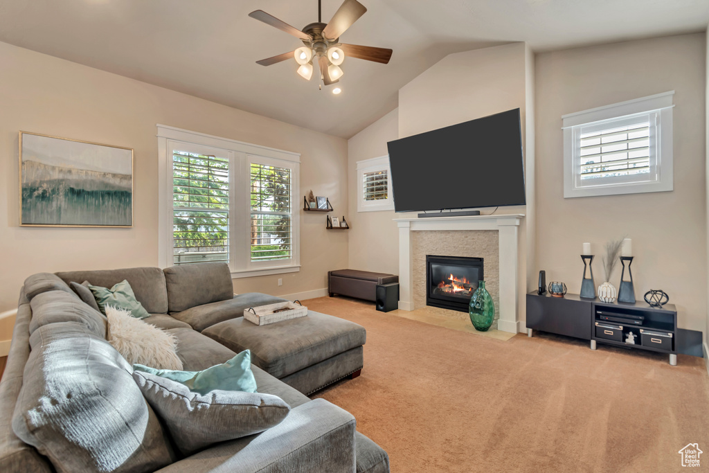 Carpeted living room with vaulted ceiling, a tiled fireplace, and ceiling fan