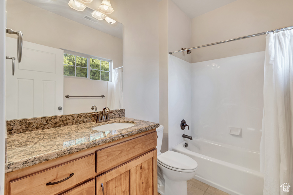 Full bathroom with vanity with extensive cabinet space, tile flooring, toilet, and shower / tub combo