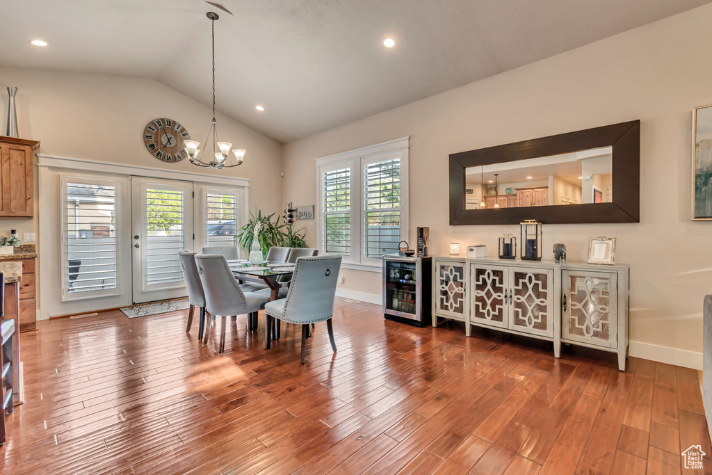 Dining space with a wealth of natural light, a notable chandelier, hardwood / wood-style flooring, and wine cooler