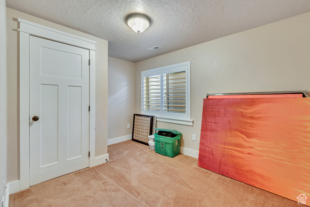 Interior space featuring a textured ceiling and light colored carpet