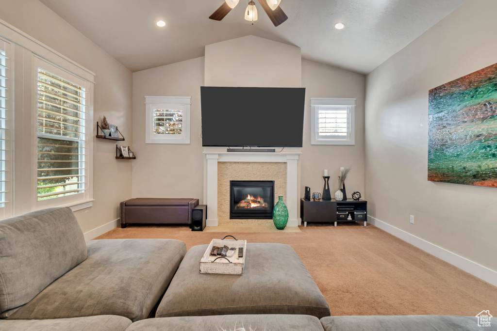 Carpeted living room featuring a wealth of natural light, ceiling fan, and lofted ceiling