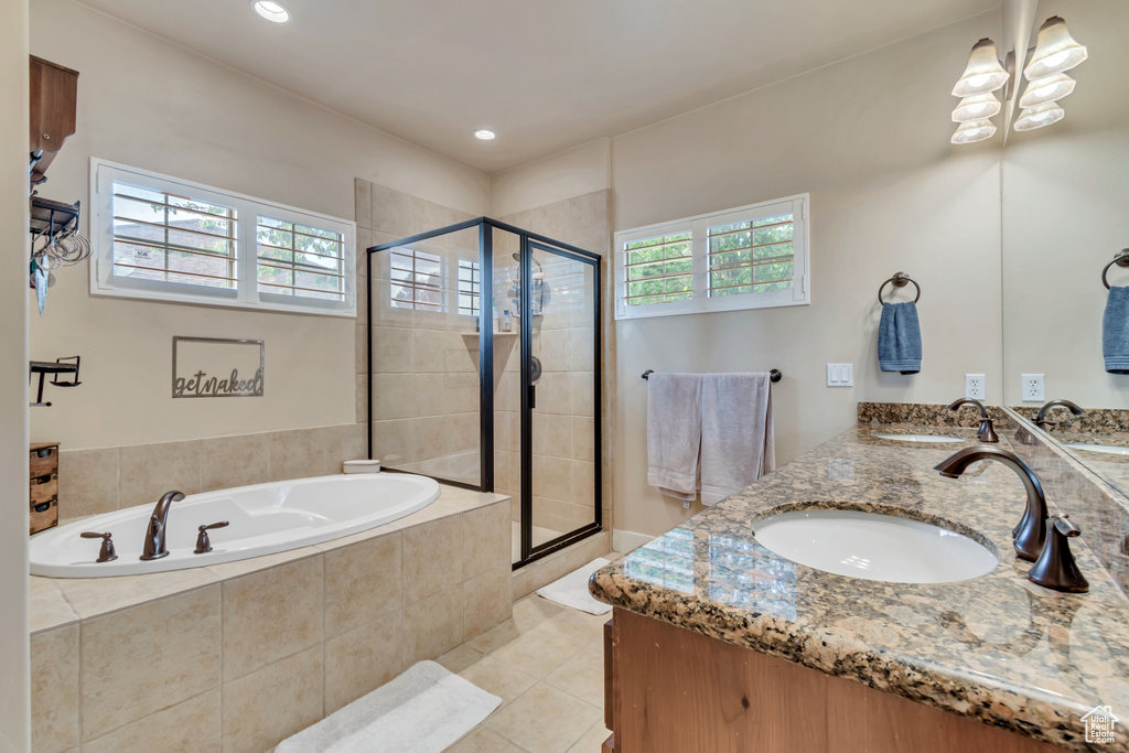 Bathroom featuring shower with separate bathtub, double sink vanity, and tile floors